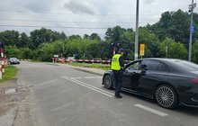 Sokista wręcza ulotkę kierowcy oczekującemu przed zamkniętym szlabanem