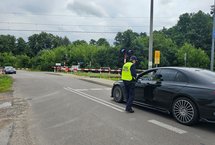 Sokista wręcza ulotkę kierowcy oczekującemu przed zamkniętym szlabanem