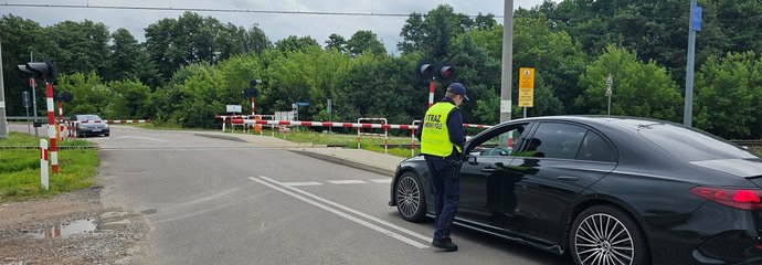Sokista wręcza ulotkę kierowcy oczekującemu przed zamkniętym szlabanem