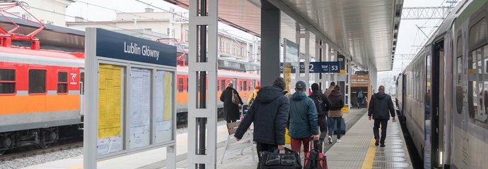 Stacja Lublin Główny, widok na podróżnych i pociągi stojące po obu stronach peronu.