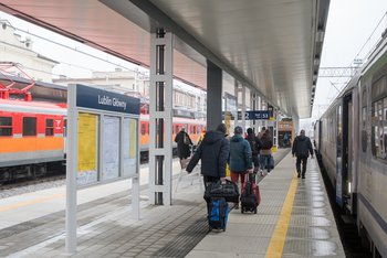 Stacja Lublin Główny, widok na podróżnych i pociągi stojące po obu stronach peronu.