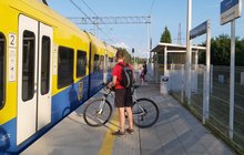 Masłońskie Natalin, podróżny z rowerem wsiada do pociągu, w tle wiata i tablica z nazwą przystanku, fot. Katarzyna Głowacka