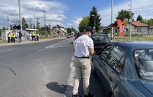 Przedstawiciel PLK SA wręcza ulotkę kierowcy w aucie przed przejazdem kolejowo-drogowym; fot. Anna Znajewska-Pawluk