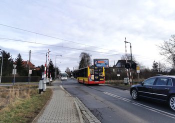 Przejazd kolejowy na ul. Krzemienieckiej we Wroclawiu. Widać autobus miejski przejeżdżający przez tory, za nim czarny samochód. Z naprzeciwka nadjeżdża biały autokar. Fot. M. Pabiańska.