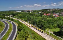 Pociąg przejeżdża obok pracującej maszyny torowej na linii kolejowej 94 w Krakowie, widok z lotu ptaka, fot. Piotr Hamarnik