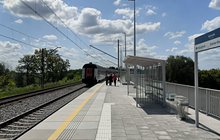 Nawierzchnia peronu w Kępnie, po prawej tablica kierunkowa i wiata, w tle pociąg i podróżni_fot.Marek Karpiński