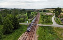 Pociąg przejeżdża przez przejazd kolejowo-drogowy w Szczepanowicach, w miejscu gdzie powstaną nowe perony, widok z lotu ptaka, fot. Piotr Hamarnik