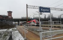 Pochylnia prowadząca na peron stacji Kępno, tablica z nazwą stacji, w tle pociąg i widok na górny poziom stacji, fot. Radek Śledziński