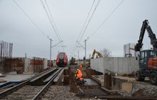 Pociąg przejeżdża przez budowany przystanek. Obok robotnicy budują docelową obudowę przejścia podziemnego. Fot. M. Pabiańska 11.24