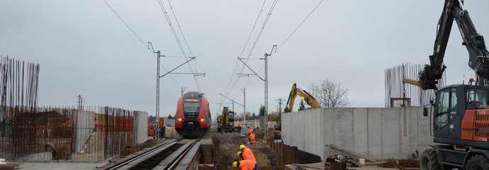 Pociąg przejeżdża przez budowany przystanek. Obok robotnicy budują docelową obudowę przejścia podziemnego. Fot. M. Pabiańska 11.24