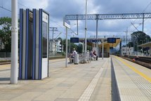 Pasażerowie na przystanku kolejowym, an pierwszym planie widać wyświetlacz z rozkładem jazdy, fot. Mateusz Ostrzyżek