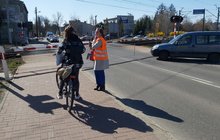 Pracownica PLK rozmawia z rowerzystką na przejeździe kolejowo-drogowym w ramach akcji edukacyjnej kampanii „Bezpieczny przejazd”. Z prawej strony widoczne też auto. Fot. Katarzyna Głowacka