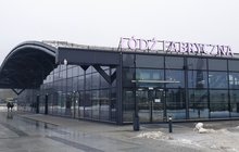 Pasażerowie idą w kierunku dworca Łódź Fabryczna. Na fasadzie dworca szyld w kolorze różowym fot. Janusz Rau