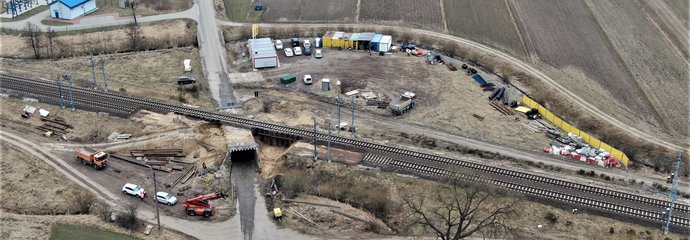 Widok z góry na tory kolejowe CMK i modernizowany wiadukt kolejowy nad drogą i plac budowy szlak Opoczno Płd. - Pilichowice, km 99,693
