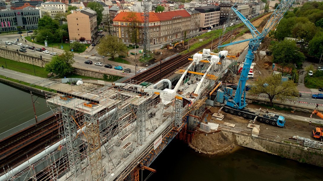 Widok na budowany most kolejowy w Krakowie nad Wisłą. Pociąg przejeżdżający przez most.