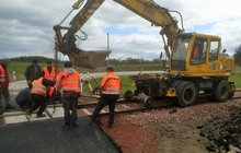 Robotnicy przy pomocy koparki kładą nową nawierzchnię na przejeździe kolejowo-drogowym, fot. Andrzej Urbanowicz PLK