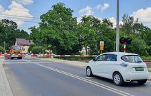 Przejazd kolejowo-drogowy zamkniętymi rogatkami. Samochody przed szlabanem.