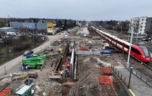 Maszyny i wykonawcy na budowie przejścia podziemnego stacji Warszawa Wawer, obok po torze jedzie pociąg, fot. Łukasz Bryłowski