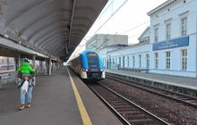 Stacja Sosnowiec, pociąg przy peronie, podróżna pod wiatą, widać budynek dworca z nazwą stacji, fot. Katarzyna Głowacka