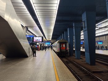 Pasażerowie na peronie stacji Warszawa Centralna, widać wjeżdzający pociag, fot. Martyn Janduła