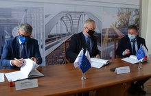3 osoby siedzące przy stole podpisują umowę na budowę wiaduktu kolejowego w Andrespolu w Łódzkiem fot. RW