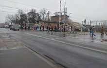 Piesi przechodzą przez przejazd na Starołęce, w tle samochód i stacja Poznań Starołęka_fot.Radek Śledziński