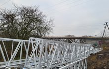 Elementy konstrukcji wsporczej dla sieci trakcyjnej na placu budowy, w tle most w Obornikach_fot.Radek Śledziński