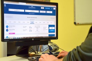 Ekran monitora z wyświetloną stroną Portal Pasażera. Przy ekranie widoczna klawiatura z rękoma osoby pracującej na niej. 