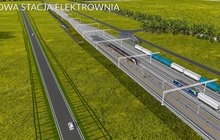 W centralnej części widać peron, a przy nim pociąg osobowy. Są tory z pociągami towarowymi oraz droga wzdłuż torów - PKP Polskie Linie Kolejowe S.A.
