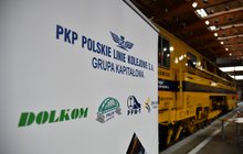 Na zdjęciu rollup z logiem PLK i spółkami zależnymi, w tle maszyna fot. Mikołaj Grabowski