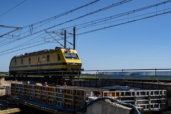 żółta drezyna PLK jadąca po torach obok mostu w przebudowie na CMK, fot. Izabela Miernikiewicz