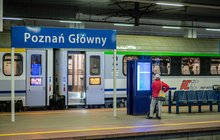 Tablica z nazwą stacji Poznań Główny, podróżna na peronie, w tle pociąg_fot.Rafał Mieszka