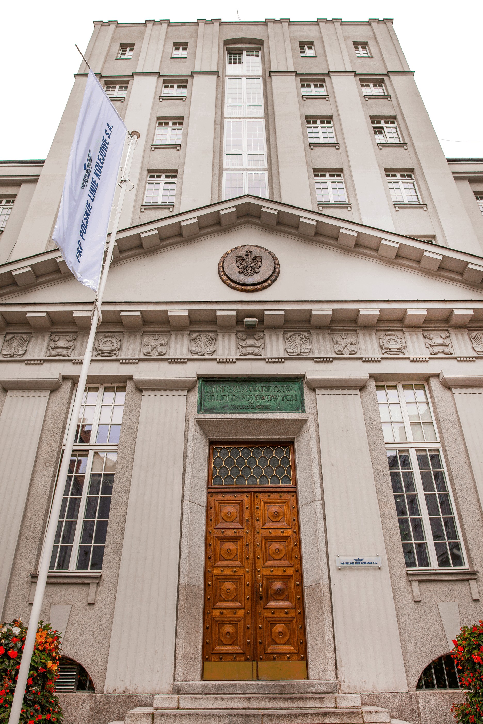 Widok na wejście do budynku od strony ulicy Wileńskiej. Nad drzwiami napis Dyrekcja Okręgowa Kolei Państwowych w Warszawie. 