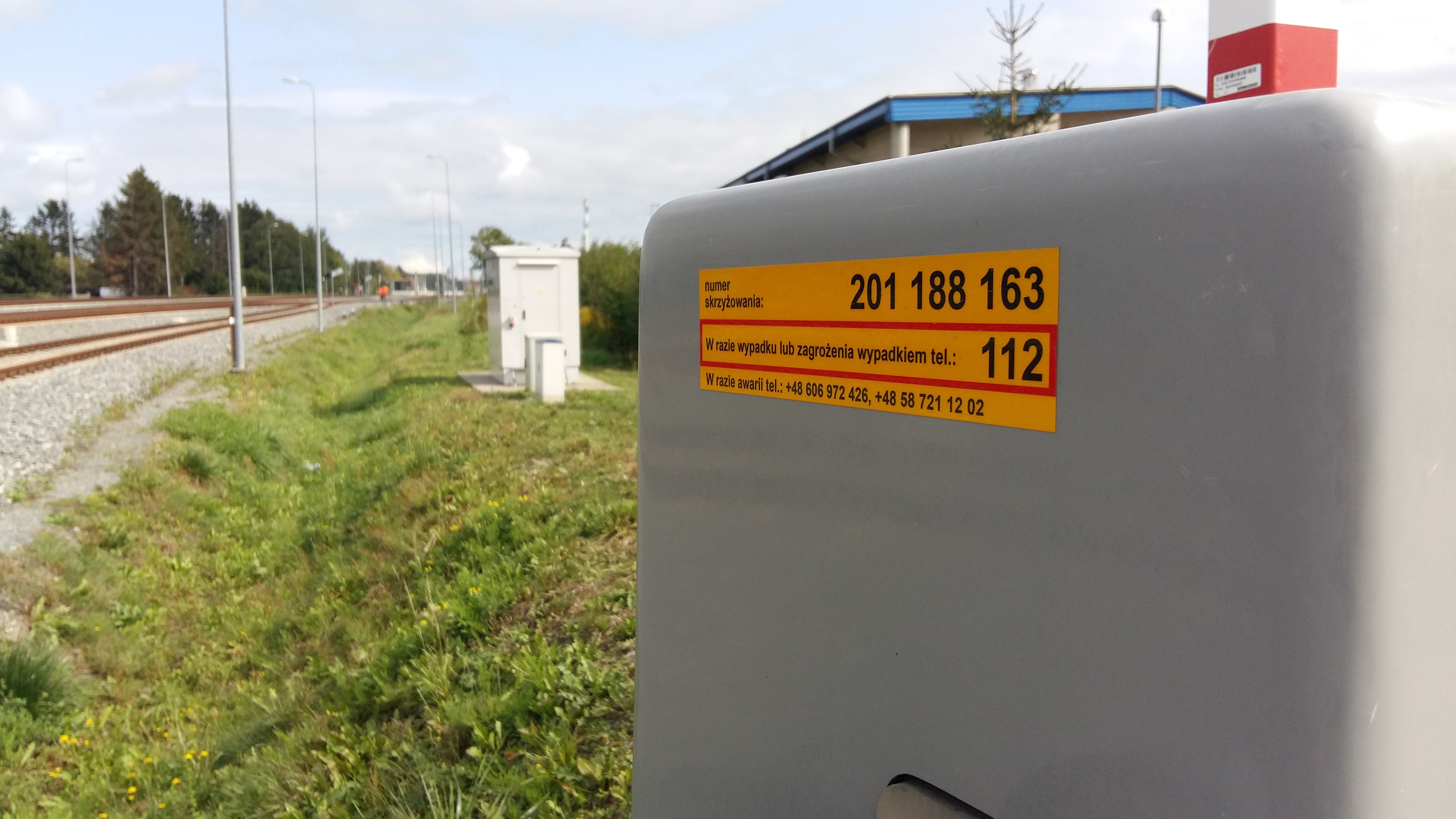 Zbliżenie na żółtą naklejkę PLK na napędzie rogatki